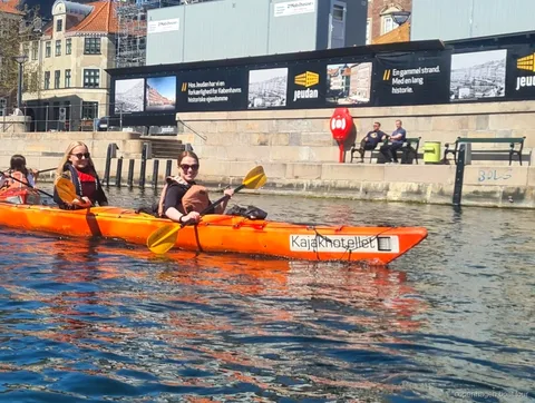 Kayakers paddling the Copenhagen harbor kayak tour past historic waterfront buildings