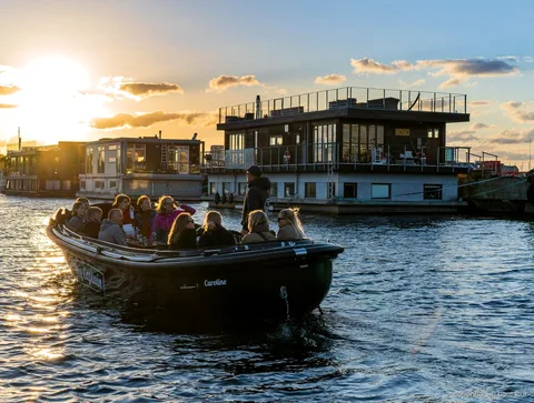 Small boat on the Copenhagen hidden gems boat tour passing modern Nordhavn buildings