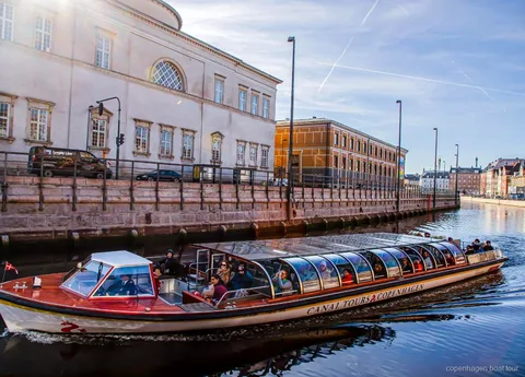 Barco del crucero por los canales de Copenhague pasando junto a edificios históricos del puerto cerca de Ved Stranden