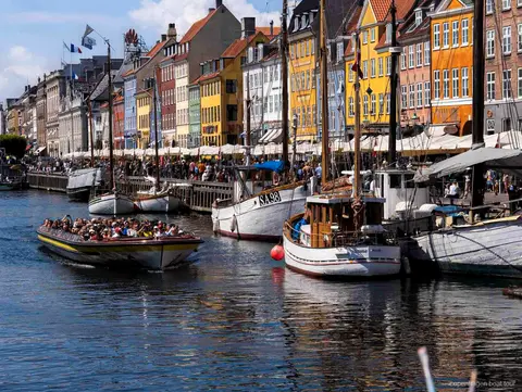 Guía narrando la ruta del crucero por los canales de Copenhague cerca de la estatua de la Sirenita