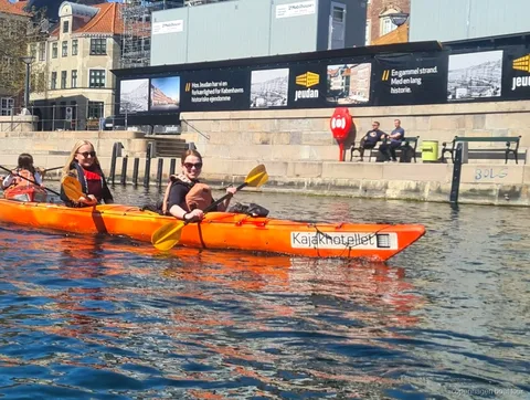 Kajakfahrer paddeln bei der Kopenhagen Kajaktour im Hafen an historischen Wasserfrontgebäuden vorbei