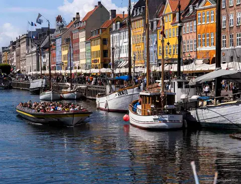 Guia narrant la ruta del creuer pels canals de Copenhaguen a prop de l'estàtua de la Sireneta