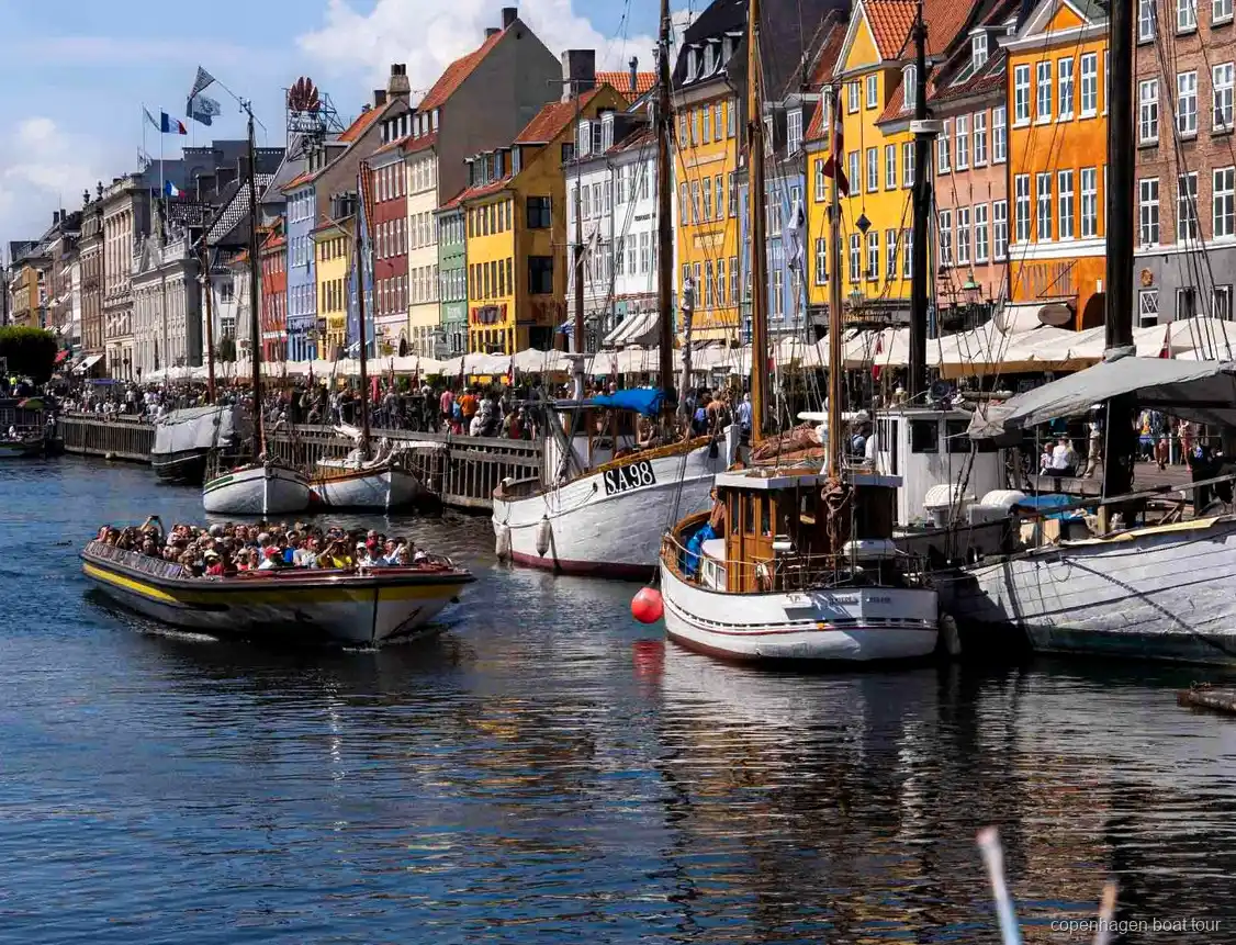 Guia narrant la ruta del creuer pels canals de Copenhaguen a prop de l'estàtua de la Sireneta