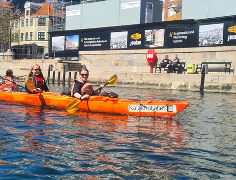 Caiaquistas remando no passeio de caiaque no porto de Copenhagen perto de prédios históricos