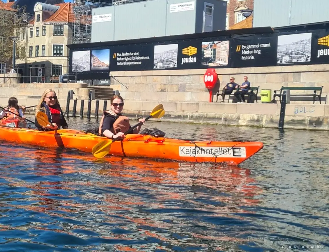Caiaquistas remando no passeio de caiaque no porto de Copenhagen perto de prédios históricos
