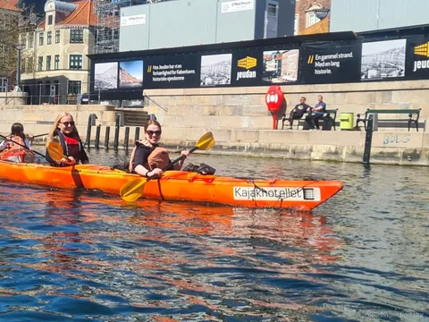 Kayakistas remando en el tour de kayak por el puerto de Copenhague junto a edificios históricos