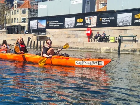Kayak che pagaiano sul tour in kayak nel porto di Copenaghen davanti a edifici storici sul lungomare